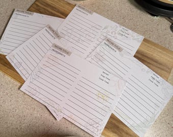 May include: Five blank recipe cards with floral designs. Each card has a space for the recipe title, ingredients, servings, prep time, and cook time.