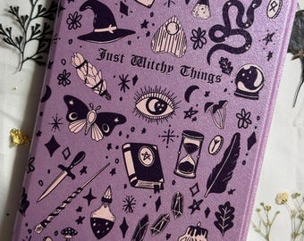 May include: A rectangular, lavender-colored case featuring a variety of witchy symbols in black. The design includes a witch's hat, a snake, a crystal ball, a skull, and the text "Just Witchy Things".