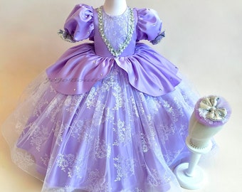 May include: A lavender satin and tulle dress with a lace overlay and a beaded bodice. The dress is on a white dress form and has a matching lavender and silver headband.