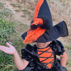 May include: A black and orange witch costume with a black sequined dress, orange lace accents, and a black witch hat with orange lace trim.
