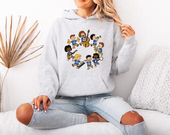 May include: A light gray hooded sweatshirt featuring a circular graphic of cartoon children in blue jerseys playing various musical instruments, including a double bass, cymbals, a keyboard, a saxophone, a trumpet, and a tambourine.