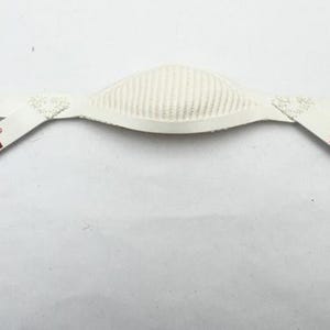 Puede incluir: Una barboquejo blanco para casco de fútbol Riddell, con una sección central acolchada y correas ajustables. El logotipo de Riddell está impreso en granate en ambos lados. Hebillas metálicas para una sujeción segura.