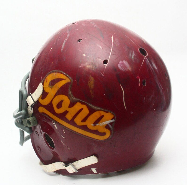 K&ouml;nnte beinhalten: Ein maroonfarbener Footballhelm mit einem wei&szlig;en Gesichtsgitter und einem gelben und goldenen "Iona"-Aufkleber an der Seite.