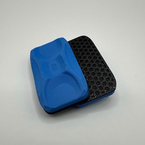 May include: A blue and black double-sided cleaning sponge. One side is textured and the other side is a honeycomb pattern.