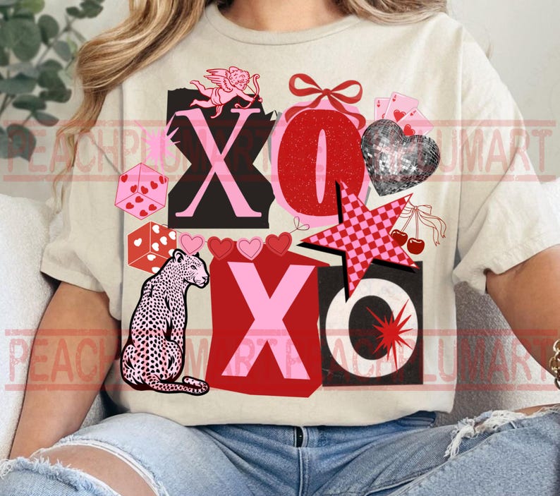 May include: Beige t-shirt with a graphic design featuring the letters X and O, hearts, dice, a leopard, a star, and cherries. The design incorporates pink, red, black, and white elements, creating a playful and romantic aesthetic.
