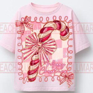 May include: A light pink t-shirt featuring a candy cane design with red and white stripes and a large bow. The words "Merry Christmas" are written in cursive. The design is framed with a pink border and two small bows.