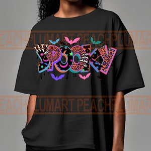 Puede incluir: Camiseta negra con un dise&ntilde;o gr&aacute;fico colorido que dice "Spooky" con murci&eacute;lagos, estrellas y detalles de estampado de leopardo.