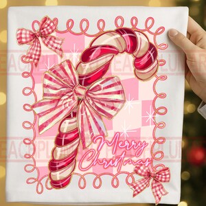 May include: A white square Christmas-themed design featuring a candy cane with red and white stripes, adorned with bows. The words "Merry Christmas" are written in cursive. The background is a pink and white checkered pattern.
