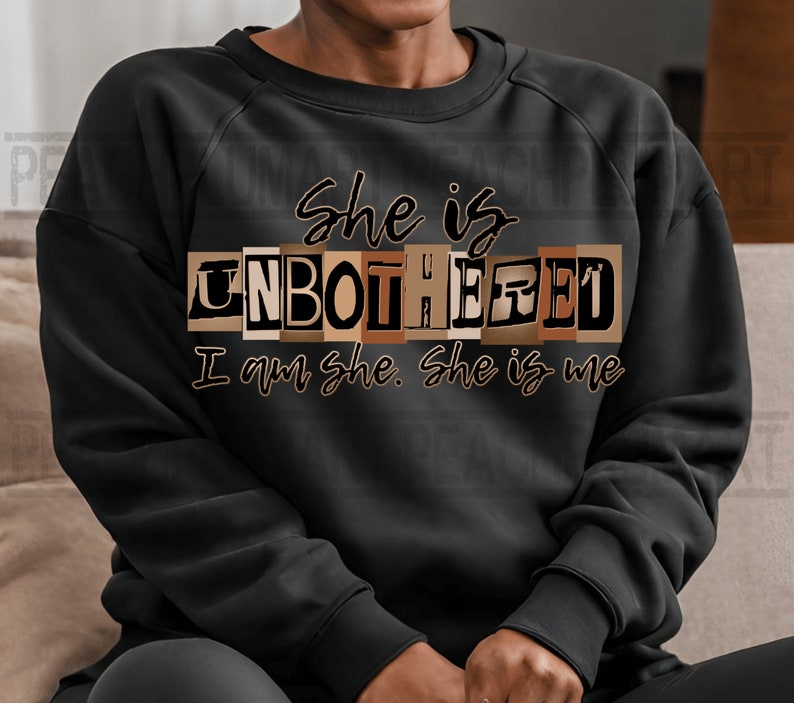 May include: Black sweatshirt with the text "She is Unbothered I am she. She is me" in brown letters. The word "Unbothered" is in a blocky font and each letter is a different shade of brown.
