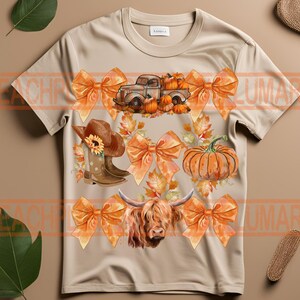 May include: A tan t-shirt with a fall-themed design featuring a truck carrying pumpkins, a highland cow, bows, boots, and pumpkins.
