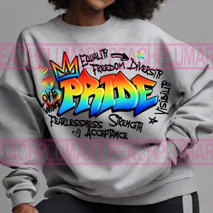 May include: A gray sweatshirt with a rainbow-colored graphic of the word "PRIDE" in a graffiti style. The graphic is surrounded by words like "Equality", "Freedom", "Diversity", "Love Wins", "Fearlessness", "Strength", and "Acceptance".