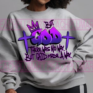 Peut inclure: Un sweat-shirt gris avec un motif graphique violet et bleu qui dit "But God" avec une couronne au-dessus du mot "God" et une croix de chaque côté. Le texte "There was no way. But God made a way." est en dessous du graphique.