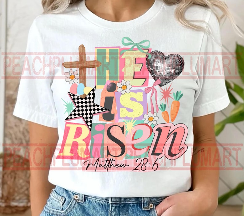 May include: White t-shirt with a colorful graphic design. The design includes the words "He is Risen" in various colors, a wooden cross, a checkered star, a sequined heart, daisies, and carrots. The text "Matthew 28:6" is also included.