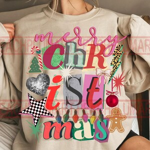 May include: Beige sweatshirt with a colorful "Merry Christmas" graphic. The design includes a disco ball heart, star, Christmas tree, gingerbread man, and other festive elements. The text is in various fonts and colors.