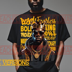 Op de afbeelding: Zwart en gouden grafisch T-shirt met een portret van een man met een kroon en zonnebril. De tekst "Bold Fearless King" staat in het geel op het shirt.