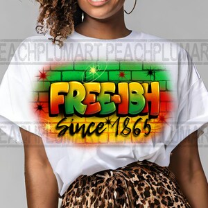 May include: White t-shirt with a graphic design of the words "Free-ish" in a graffiti style with a brick wall background and the text "Since 1865".