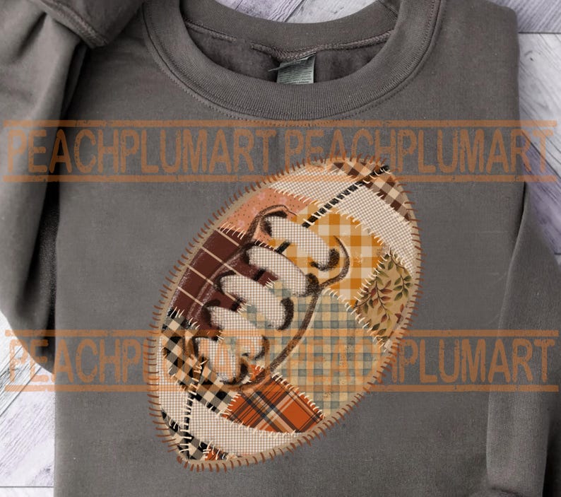 May include: Gray sweatshirt with a football-shaped patch. The patch is made of various fabric patterns in shades of brown, orange, and cream, with the word "Fall" stitched in white.