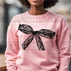 K&ouml;nnte beinhalten: Ein rosa Sweatshirt mit einem schwarzen Spitzen-Schleifendesign.