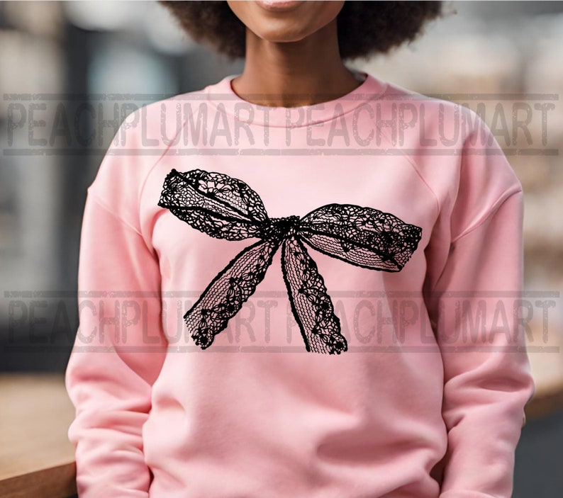 K&ouml;nnte beinhalten: Ein rosa Sweatshirt mit einem schwarzen Spitzen-Schleifendesign.