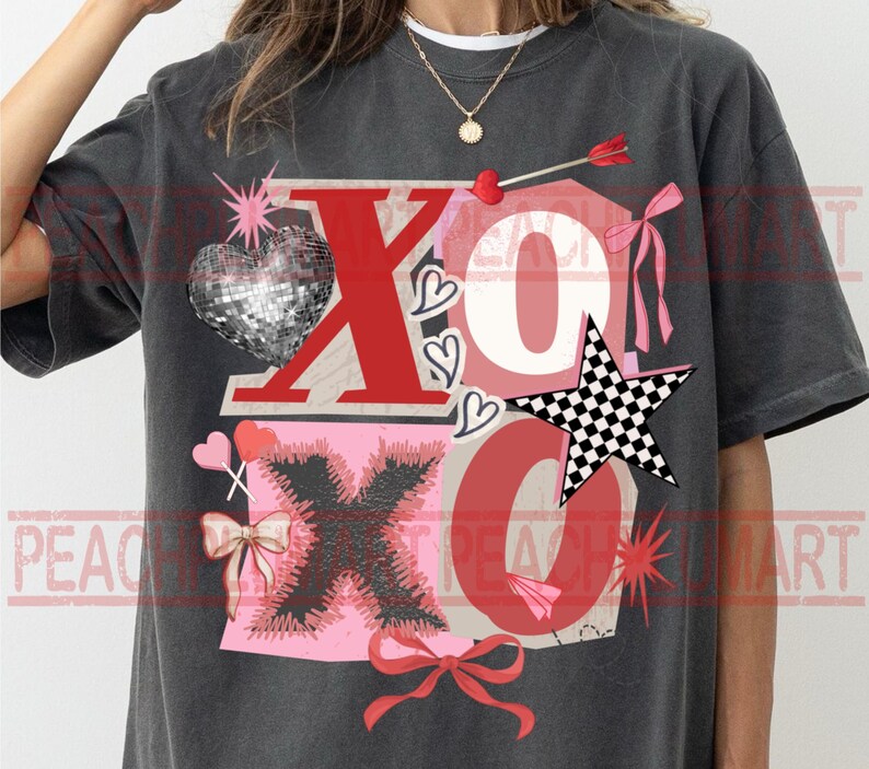 May include: Dark gray t-shirt with a graphic design featuring the letters "XO" in red and pink, a disco ball heart, a checkered star, and bow accents. The shirt has a vintage, distressed look.