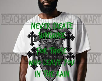 May include: White t-shirt with a black and white illustration of a person wearing a bandana and a cross graphic. The text "Never create sunshine for those who leave you in the rain" is printed in green.