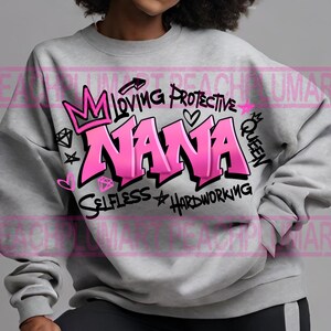 May include: Gray sweatshirt with a pink graphic design that says "NANA" with a crown, hearts, diamonds, and the words "Loving, Protective, Queen, Selfless, Hardworking".
