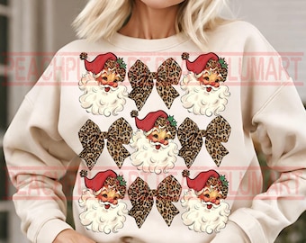 May include: A cream-colored sweatshirt with a festive design featuring multiple images of Santa Claus wearing a red hat and white beard. Each Santa is surrounded by a leopard print bow.