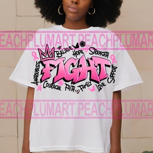 Op de afbeelding: Wit T-shirt met een roze grafisch ontwerp met de tekst "FIGHT" in grote letters. De grafiek bevat ook de woorden "Believe", "Hope", "Strength", "Awareness", "Courage", "Faith", "Family", "Love" en "Support".