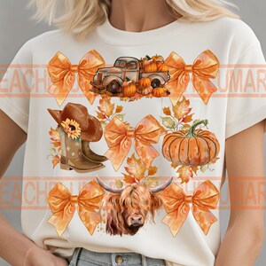 May include: A white t-shirt with a fall-themed design featuring a truck carrying pumpkins, a cow, cowboy boots, and orange bows. The design is surrounded by fall leaves.