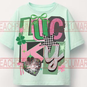 May include: A light green t-shirt with the word "LUCKY" in a colorful graphic design. The design includes a four-leaf clover, a disco ball heart, a star with a checkered pattern, and a green bow.