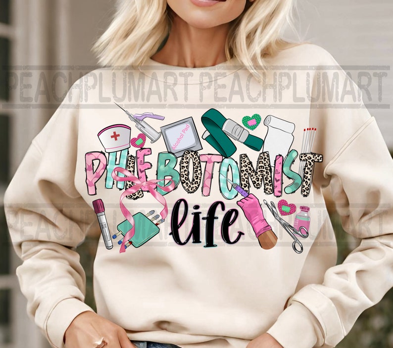 May include: A cream-colored sweatshirt with the text "Phlebotomist life" in pink, green, and black letters. The text is surrounded by various medical-themed illustrations, including a tourniquet, alcohol prep pad, bandages, and a syringe.