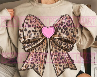 May include: A beige sweatshirt with a large leopard print bow and a pink heart in the center.