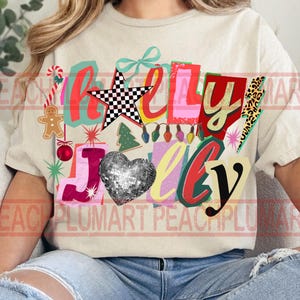 K&ouml;nnte beinhalten: Cremefarbenes T-Shirt mit einem farbenfrohen Aufdruck mit der Aufschrift "Holly Jolly". Das Design umfasst einen karierten Stern, ein Herz aus Discokugeln und Weihnachtselemente wie einen Lebkuchenmann und eine Zuckerstange.