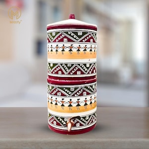 May include: A white ceramic water filter with a red, green and yellow geometric pattern. The filter has three tiers and a small spout on the bottom.