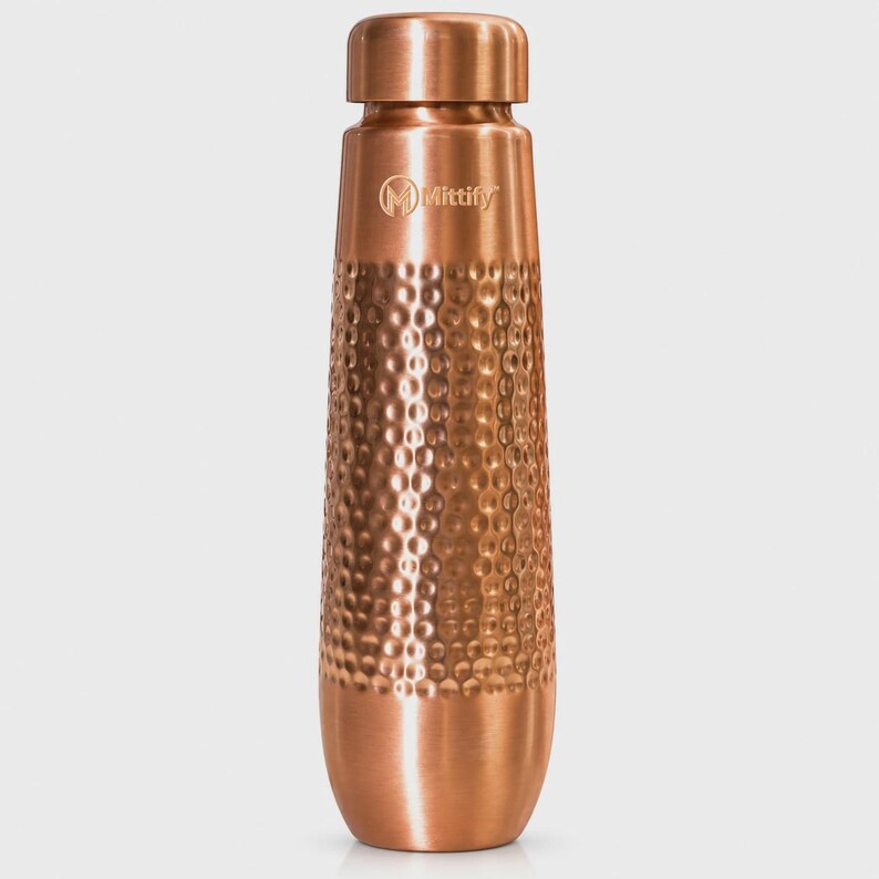 May include: A copper-colored metal water bottle with a smooth neck and base, featuring a textured hammered finish on the main body. The brand name Mittify and a circular logo are printed in a light color on the upper section of the bottle.