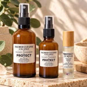 Op de afbeelding: Twee amberkleurige glazen sprayflessen en één kleine glazen rollerfles met een bamboe dop. De etiketten vermelden Sacred Cleanse Aura Spray Protect en Protect Oil Roller, met ingrediënten zoals Palo Santo, Florida Water en Sandelhout.