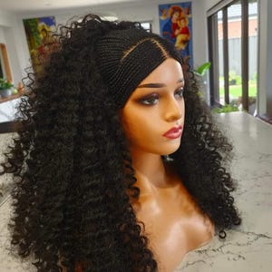 May include: A black wig with a curly afro style, featuring a braided crown with a parting in the middle. The wig is styled on a mannequin head.
