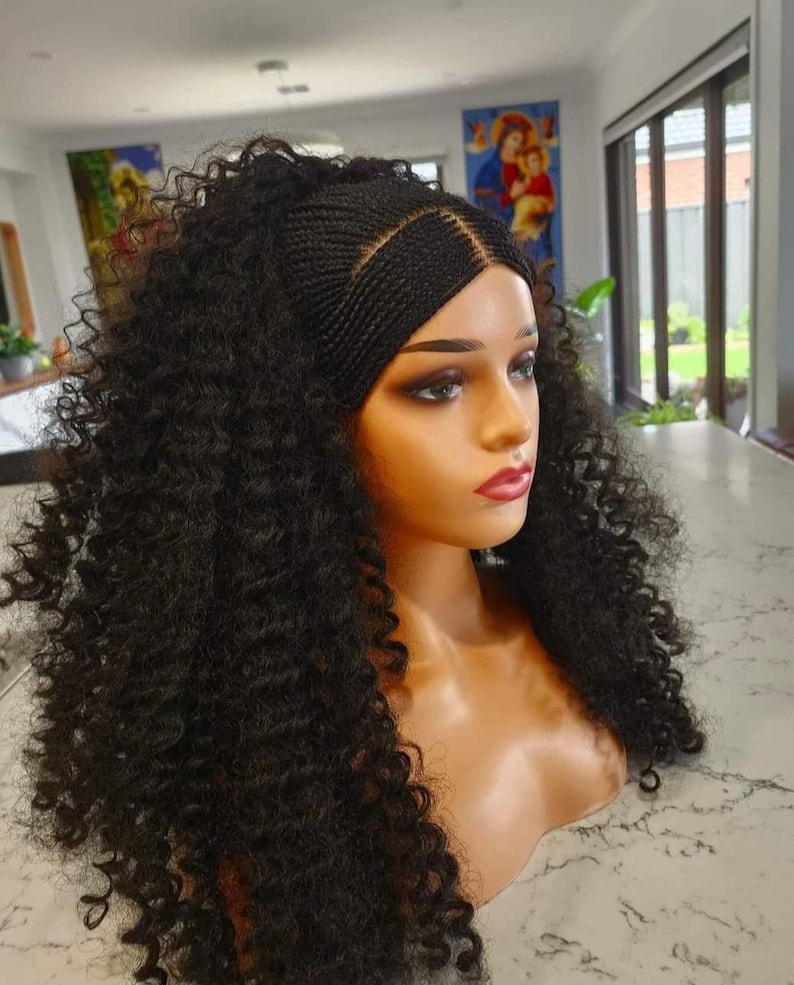 May include: A black wig with a curly afro style, featuring a braided crown with a parting in the middle. The wig is styled on a mannequin head.