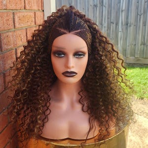 May include: A brown and blonde curly wig with a braided crown. The wig is on a mannequin head.