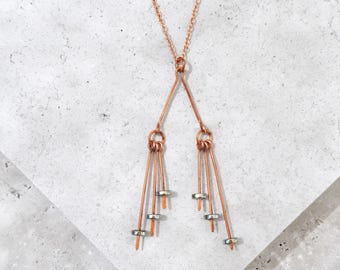 May include: A copper necklace with a V-shaped pendant and four dangling strands of copper wire with silver beads at the ends.