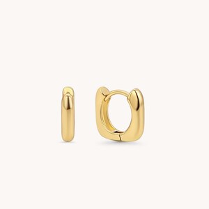 May include: A pair of gold hoop earrings. The earrings are small and have a square shape.