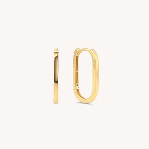 May include: A pair of gold-toned oval hoop earrings. The earrings are made of a smooth, shiny metal.