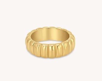 May include: A gold-toned ring with a ridged, textured band.