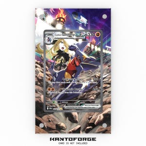 Puede incluir: Una tarjeta coleccionable de Pokémon enmarcada con Cynthia's Garchomp EX. La tarjeta muestra una colorida ilustración de un personaje con una criatura azul y amarilla con forma de dragón. La tarjeta está sobre un fondo de paisaje rocoso y cielo púrpura. El texto "KANTOFORGE" está en la parte inferior.