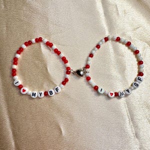 May include: Two beaded bracelets with red and white beads. One bracelet says "I love my BF" and the other says "I love my GF".