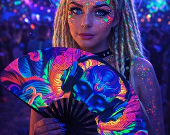 May include: A black hand fan with a vibrant, swirling design in neon colors of blue, pink, orange, and green. The fan is held in front of a person with face paint and hair styled with dreadlocks, in a crowd with neon lights.
