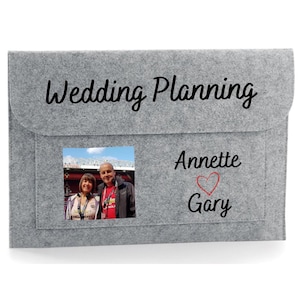 May include: Grey felt folder with a pocket for a photo. The folder has the text "Wedding Planning" on the front. The pocket contains a photo of a couple. The text "Annette ♥ Gary" is below the photo.