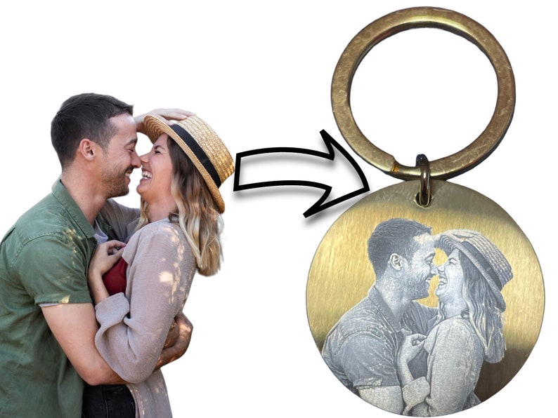 May include: A gold-toned keychain with a round metal charm featuring a black and white engraved image of a couple embracing.