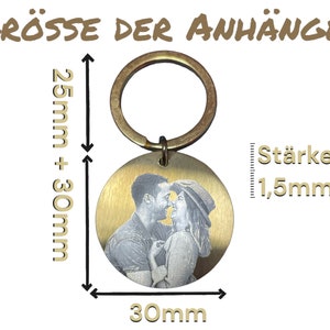 May include: A gold-colored metal keychain with a round, engraved photo charm. The charm is 30 mm in diameter and 1.5 mm thick. The keychain is 25 mm + 30 mm in length.