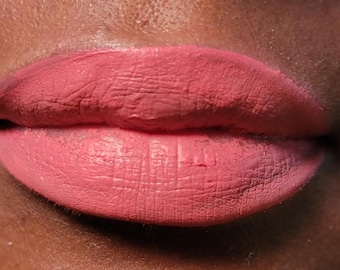Puede incluir: Primer plano de los labios de una persona con un labial mate de color rosa. El labial tiene un acabado liso y uniforme.